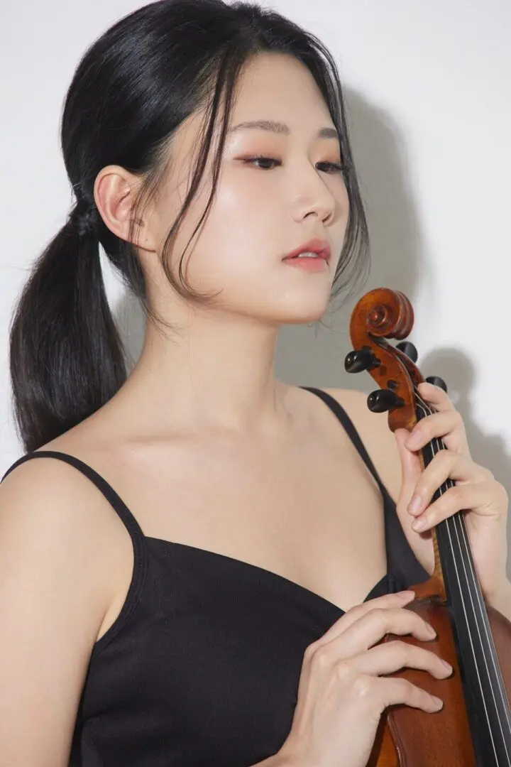 Woman playing a violin with focused expression.