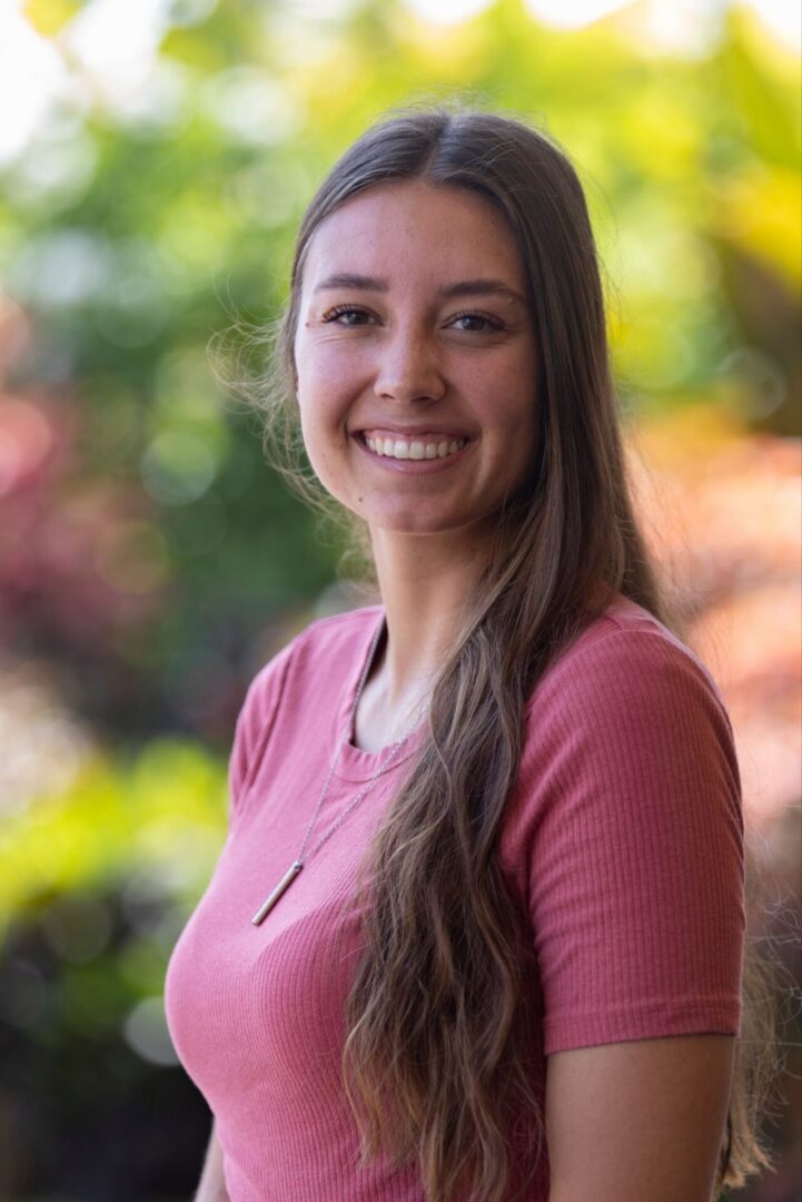 Smiling woman with long hair in natural setting.