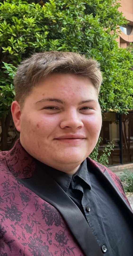 Smiling individual in a stylish suit outdoors.